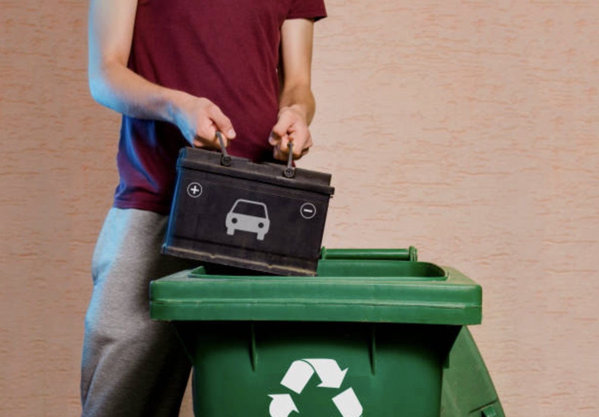 Vehicle Batteries Recycling | Man throwing old empty car battery in garbage disposal with recycling symbol