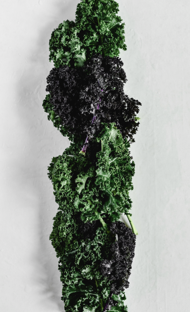 Vertical shot of fresh organic kale on a white surface, showcasing healthy greens.